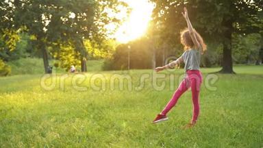 小女孩在绿色的草地上玩，同时做一个杂技轮。 年轻的运动小子有一个非常好的心情。